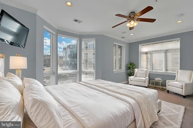 a bedroom with a large bed a flat screen tv and a large window
