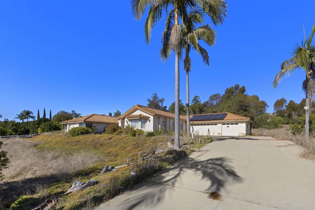 a view of a house with a yard and palm trees
