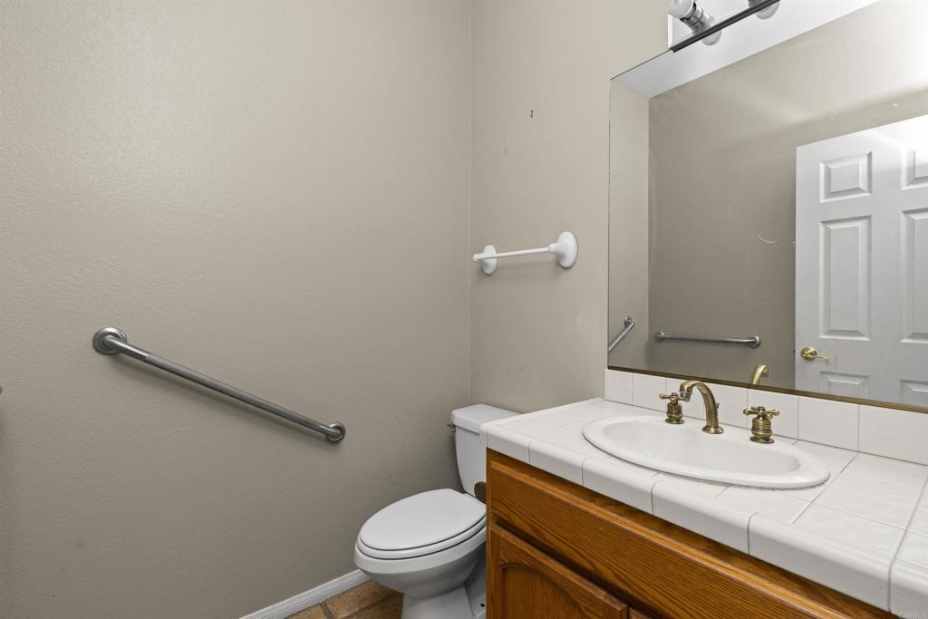 1007 Capra Way Fallbrook, CA 92028 - Photo 30 of 44 a bathroom with a granite countertop sink a toilet and a mirror