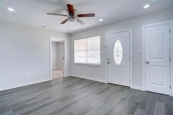 an empty room with wooden floor and windows