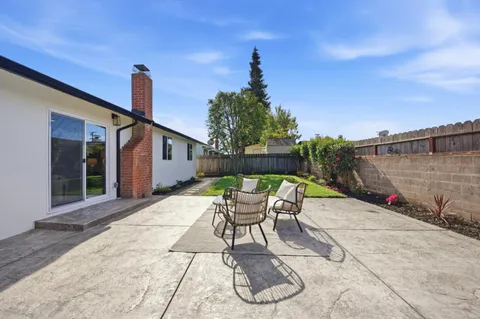 a patio with table and chairs and potted plants