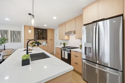 a kitchen with stainless steel appliances granite countertop a refrigerator a stove and a sink with wooden floor