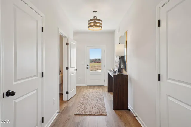 a view of a hallway view with wooden floor and a bathroom