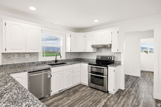 4155 Johnson Road Nibley, UT 84321 - Photo 11 of 71 Kitchen with stainless steel appliances, dark stone counters, white cabinets, ornamental molding, and recessed lighting