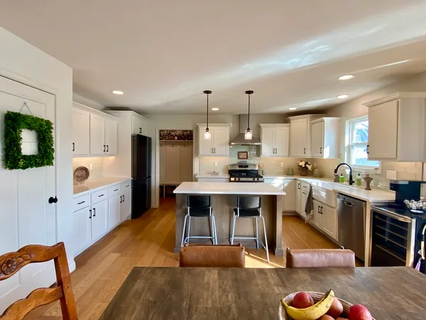 a large kitchen with cabinets wooden floor white stainless steel appliances and white cabinets