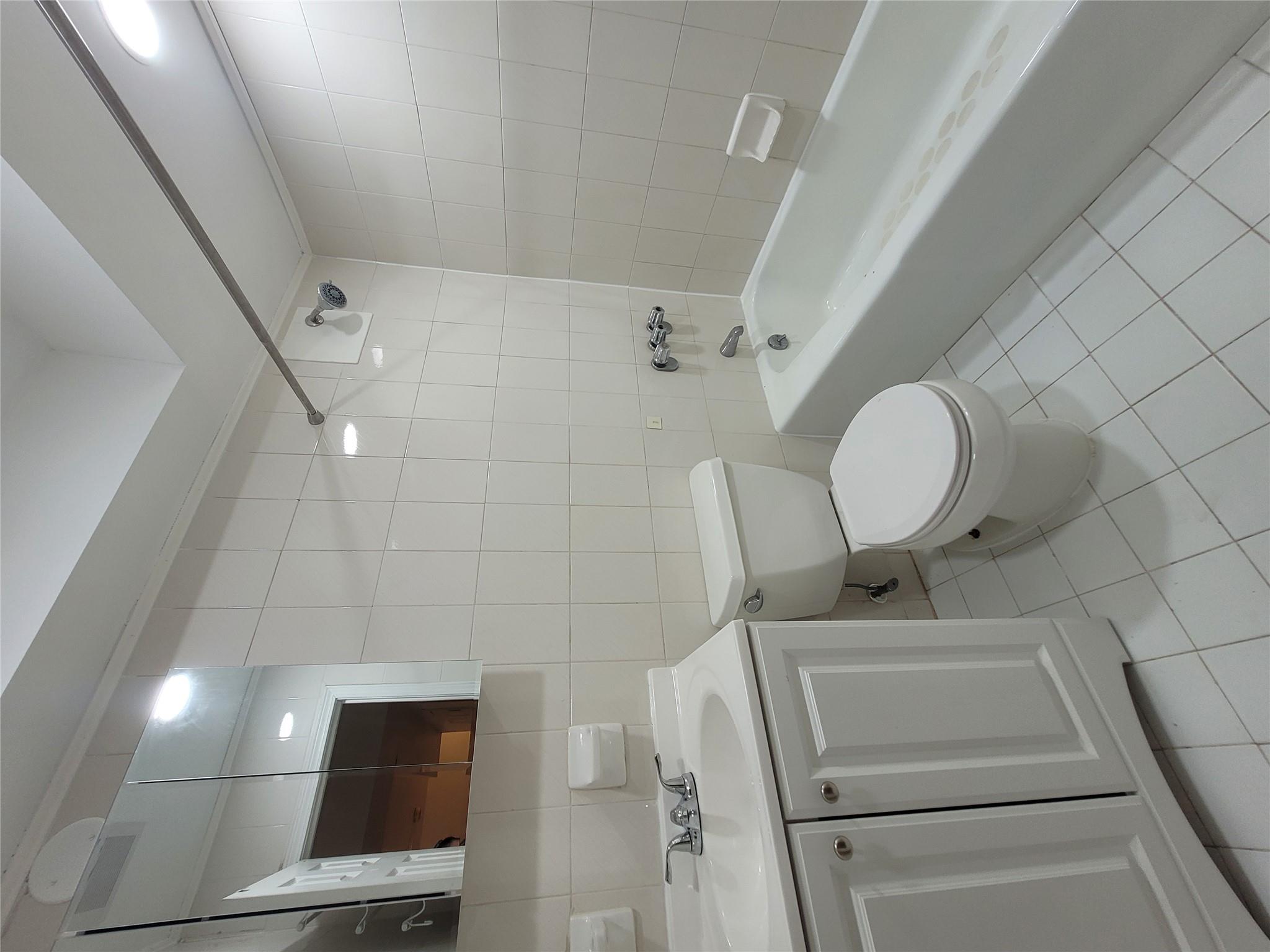 1124 67th Street, Unit A3 Brooklyn, NY 11219 - Photo 15 of 20 Full bath featuring tile patterned floors, toilet, vanity, shower / tub combination, and tile walls