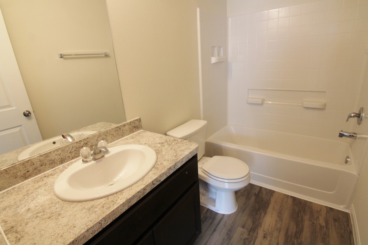 5486 Quail Cove Lane Houston, TX 77053 - Photo 5 of 7 a bathroom with a granite countertop toilet a sink and a bathtub
