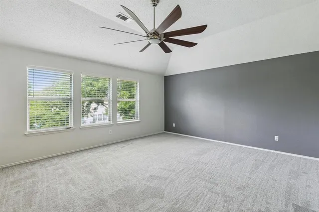 an empty room with windows and ceiling fan