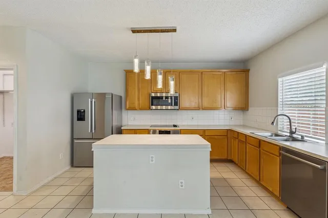 a utility room with stainless steel appliances granite countertop a sink stove and refrigerator