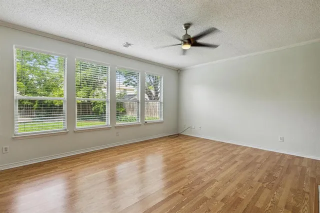 a view of an empty room with a window and wooden floor