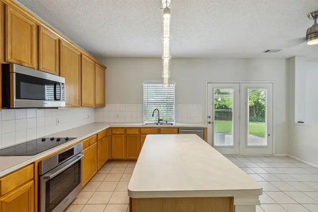 a large kitchen with stainless steel appliances granite countertop a stove a sink and a microwave