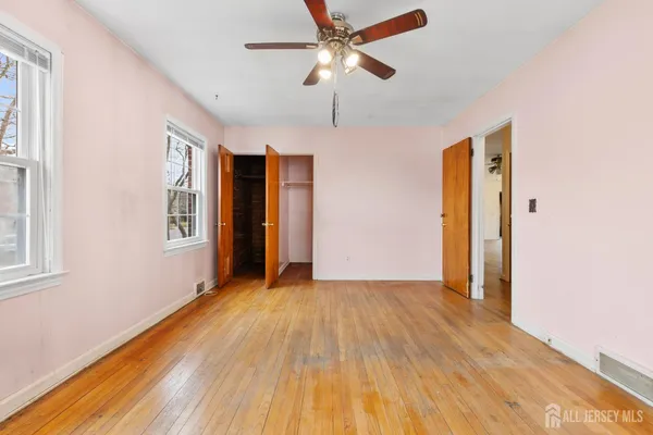 a view of an empty room with window and wooden floor