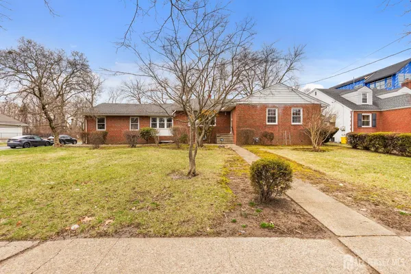 a front view of a building with large trees