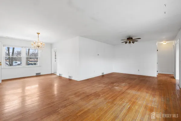 a view of empty room with wooden floor and windows