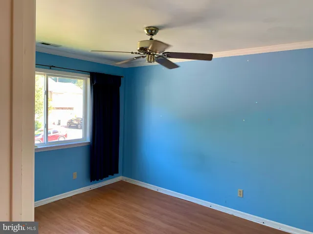an empty room with wooden floor chandelier fan and windows