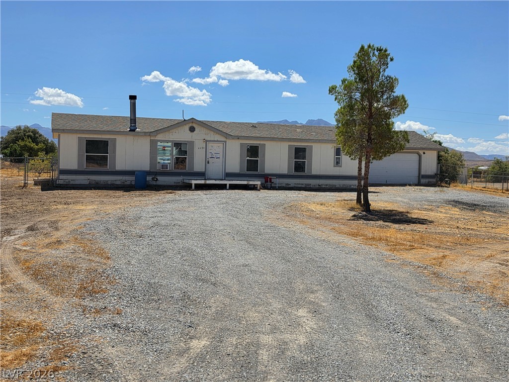 4231 West Wilson Road Pahrump, NV 89048 - Photo 1 of 19 A long gravel driveway leads to this classic single-story home featuring an attached garage.