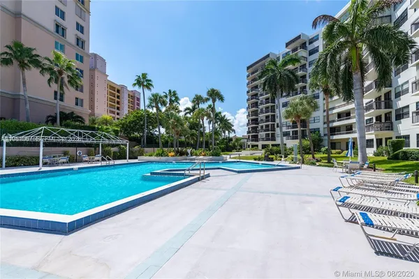 a view of a swimming pool with a lawn chairs and palm trees