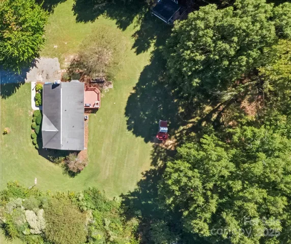 an aerial view of residential house with outdoor space and trees all around