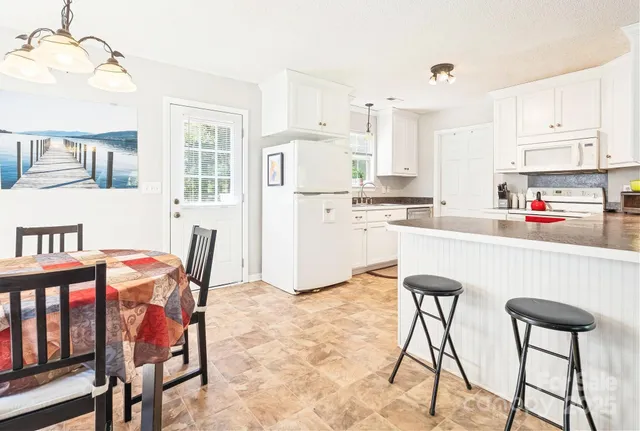 a kitchen with stainless steel appliances kitchen island granite countertop a table chairs and a refrigerator