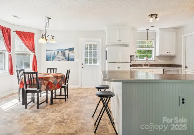 a kitchen with stainless steel appliances granite countertop a stove top oven a sink a dining table and chairs with wooden floor