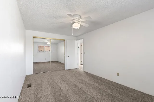 an empty room with closet and a ceiling fan