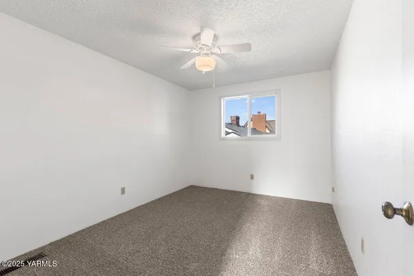 an empty room with chandelier fan and closet area