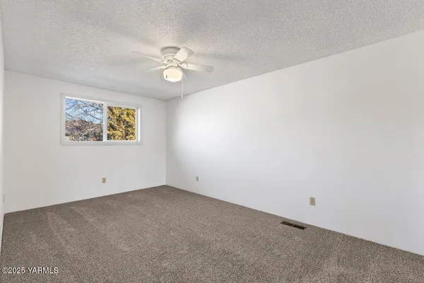 an empty room with closet and a ceiling fan