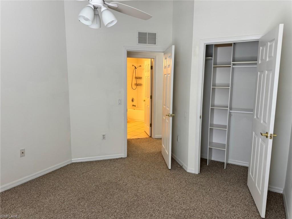 860 Hampton Circle, Unit 165 Naples, FL 34105 - Photo 22 of 38 an empty room with windows closet and chandelier fan
