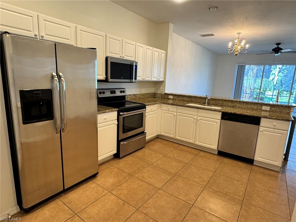 860 Hampton Circle, Unit 165 Naples, FL 34105 - Photo 3 of 38 a kitchen with stainless steel appliances granite countertop a refrigerator a stove a sink and a microwave
