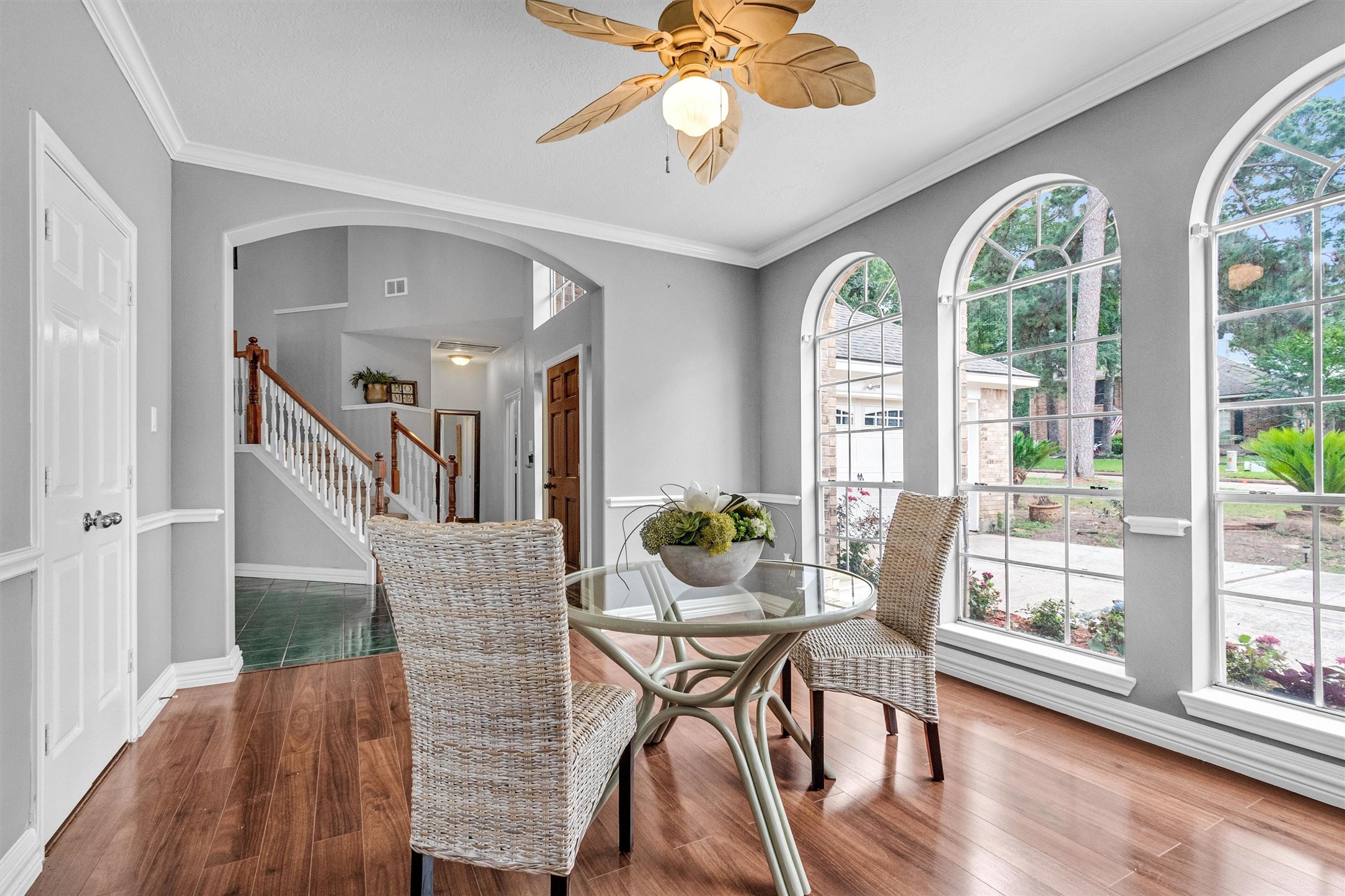 23 Alba Road Montgomery, TX 77356 - Photo 2 of 37 Bright dining area with large arched windows, wood flooring, and a ceiling fan. Offers a view of the front yard, and features a staircase with wooden railing leading to the upper level.