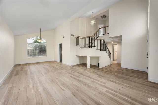 a view of an empty room with window and wooden floor