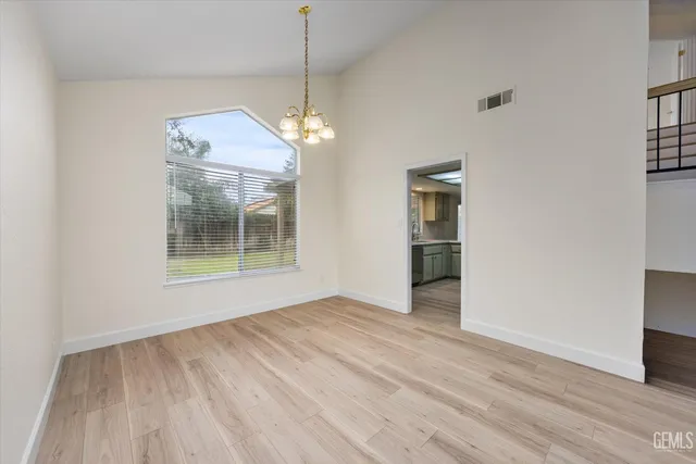 a view of an empty room with wooden floor fireplace and a window