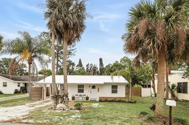 a view of a house with a yard and palm trees