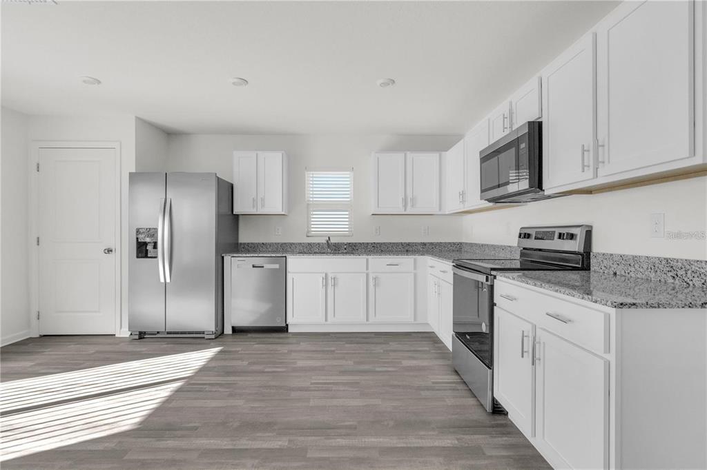 1623 Indiana Loop Sumterville, FL 33585 - Photo 2 of 6 a kitchen with stainless steel appliances granite countertop a refrigerator sink and white cabinets