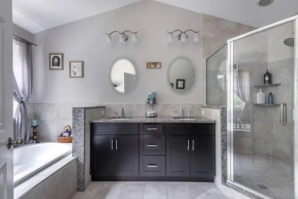a spacious bathroom with a granite countertop sink a mirror and shower