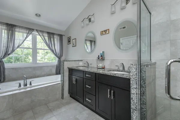 a spacious bathroom with a tub sink and mirror