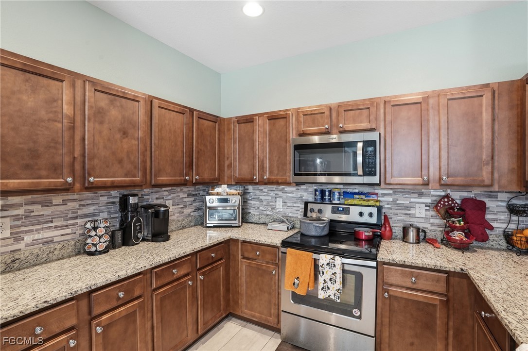1004 Hamilton Street Immokalee, FL 34142 - Photo 19 of 45 a kitchen with stainless steel appliances granite countertop a sink a stove and a microwave