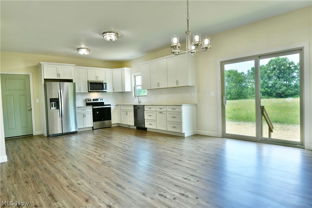 6834 Palmyra Road Southwest Warren, OH 44481 - Photo 11 of 33 Kitchen featuring stainless steel appliances, white cabinetry, plenty of natural light, and hardwood / wood-style flooring