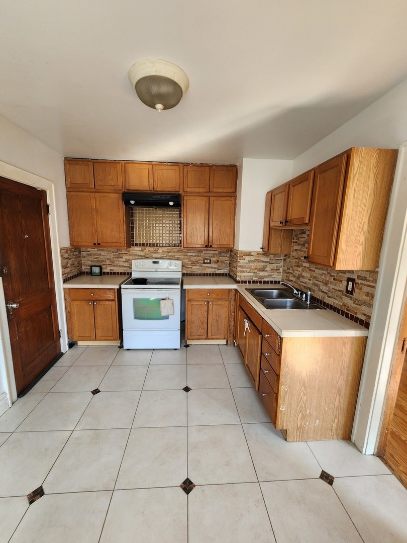 600 Sunderlin Street Waukegan, IL 60085 - Photo 11 of 12 a kitchen with stainless steel appliances granite countertop a stove top oven and cabinets