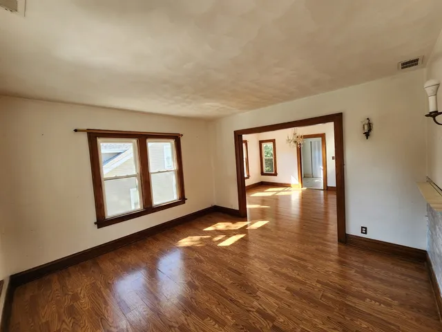 a view of an empty room with window and wooden floor
