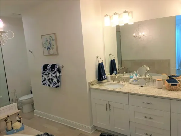 a bathroom with a granite countertop sink mirror vanity and toilet