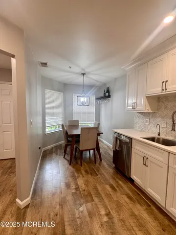 a kitchen with stainless steel appliances granite countertop a stove a sink a dining table and chairs with wooden floor