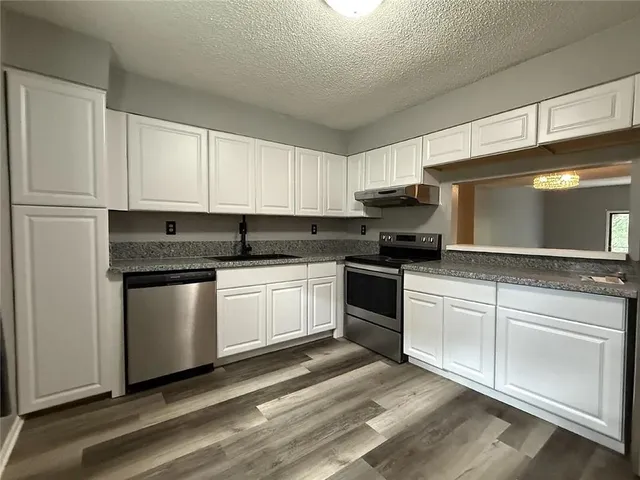 a kitchen with granite countertop white cabinets and white appliances