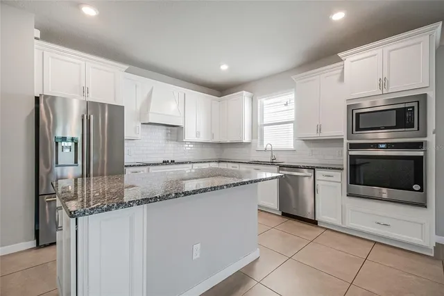 a kitchen with stainless steel appliances granite countertop a refrigerator sink and microwave