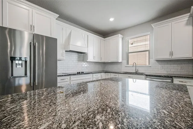 a kitchen with granite countertop a refrigerator sink and cabinets