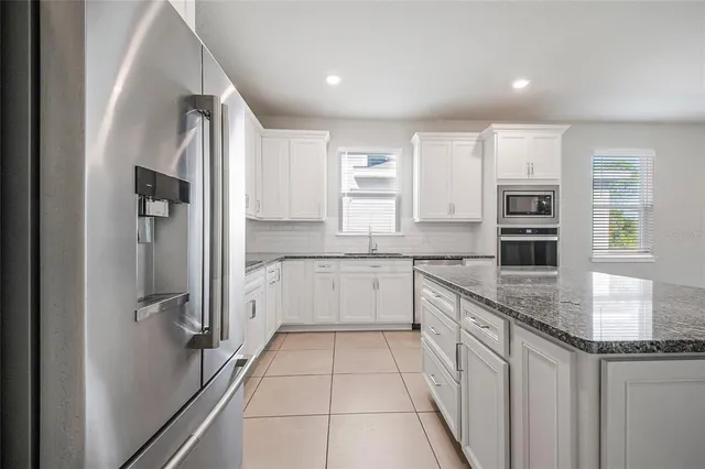 a large kitchen with stainless steel appliances granite countertop a refrigerator and a stove top oven