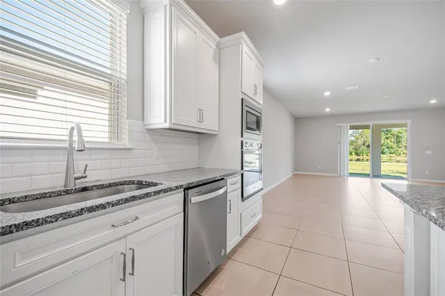 a kitchen with stainless steel appliances granite countertop a sink and a white cabinets