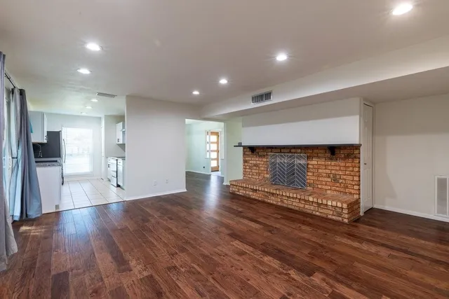 a view of empty room with wooden floor and fireplace