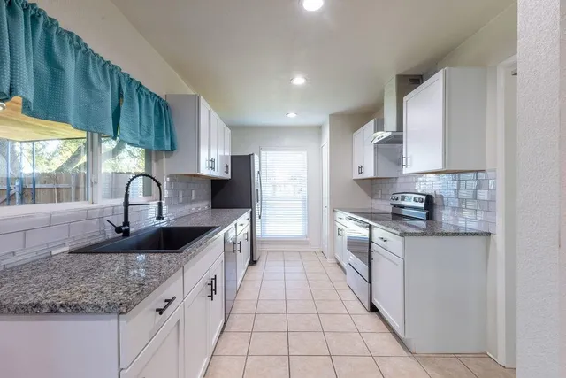 a kitchen with granite countertop a sink a stove and cabinets