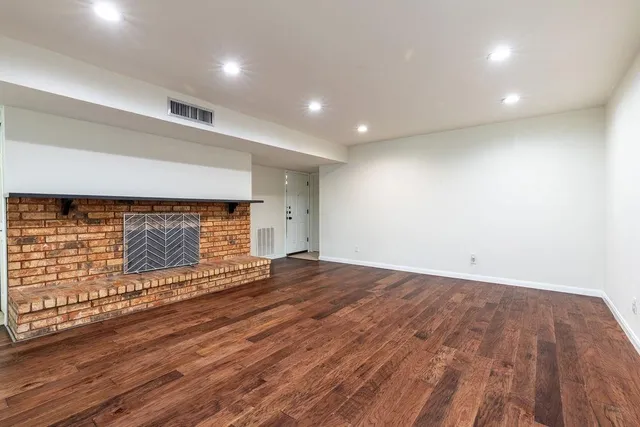 an empty room with wooden floor and a fireplace